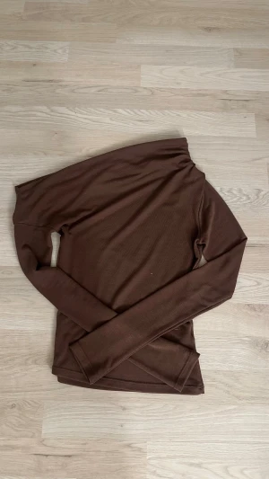 Brun långärmad topp från Nelly  - Säljer en enkel och stilren brun långärmad topp från Nelly i storlek xs. Toppen är offshoulder på ena axeln och är i väldigt skönt tyg. Säljer då den inte kommer till användning och är lite för liten. 