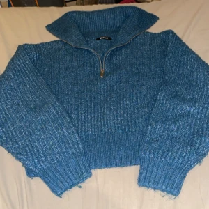 Blågrön stickad  tröja med half zip Gina Tricot - Mysig blågrön  stickad tröja från Gina Tricot i storlek S. Tröjan har en hög krage och en half zip-dragkedja framtill. Ribbstickade muddar och grovstickad struktur ger en cool och avslappnad vibe. Perfekt för kyliga dagar.