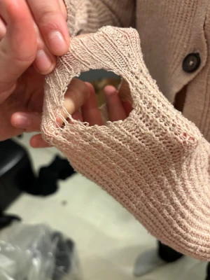 Beige stickad kofta med knappar - Säljer en beige stickad kofta med grov ribbad struktur och v-ringad hals. Koftan har tre stora knappar framtill och är croppad i modellen. Långärmad och mjuk, perfekt för lager-på-lager. Passar dig som gillar chill och enkel stil.