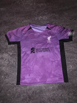 Liverpool match kläder - Liverpool FC matchställ med lila tröja och svarta shorts.