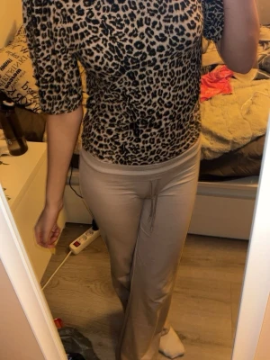 Leopardmönstrad topp med trekvartsärm - Säljer en snygg topp med leopardmönster i beige och svart. Toppen har trekvartsärm och är figurnära med rund hals. Perfekt för dig som gillar djurmönster och vill sticka ut lite extra. Materialet känns mjukt och stretchigt, troligen polyester eller bomull.