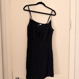 Kort klänning  - Kort svart klänning med urringning och Knut. 