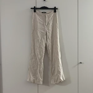 Beiga kostymbyxor från Gina Tricot - Snygga beiga byxor från Gina Tricot i storlek 36. De har rak passform och är tillverkade i ett mjukt bomullsmaterial. Byxorna har hög midja och stängs med dold dragkedja framtill. Perfekta för en clean och stilren look. Sitter så fint på har inget strykjärn😬