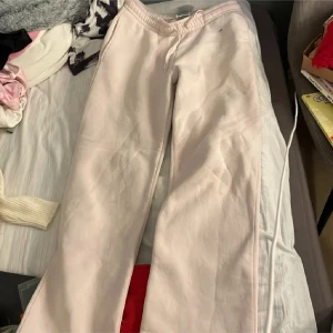 Ljusrosa mjukisbyxor med snörning - Ljusrosa mjukisbyxor med elastisk midja och snörning. Byxorna är tillverkade i mjukt bomullsmaterial och har en relaxed passform. Perfekta för chill dagar hemma eller när du vill vara extra bekväm.