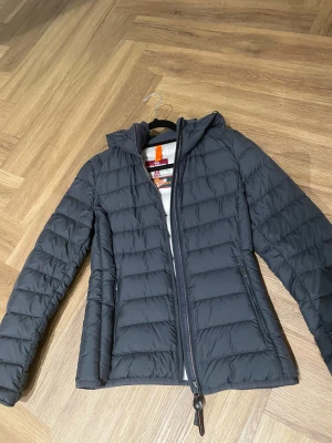 Svart pufferjacka från Parajumpers - Säljer en svart pufferjacka från Parajumpers i storlek S. Jackan har huva, quiltad design och dragkedja framtill. Superlätt material som är perfekt för kyliga dagar. Snygg och enkel att matcha med din vardagsstil.