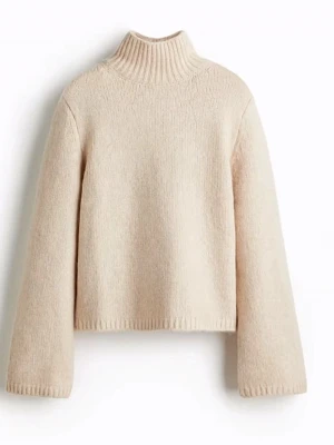 Beige stickad polotröja - Säljer en beige stickad polotröja med ribbad hög krage och långa ärmar. Tröjan har en enkel och stilren design, perfekt för att hålla värmen under kyliga dagar. Mjuk och skön känsla tack vare det stickade materialet.