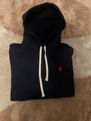 Ralph Lauren hoodie – mörkblå - Mörkblå hoodie från Ralph Lauren i klassisk och tidlös design. Tröjan är märkt storlek S men är något liten i storleken och passar därför bättre som XS. Tillverkad i mjukt och bekvämt material, perfekt för både vardag och fritid. Priset kan diskuteras vid snabb affär.