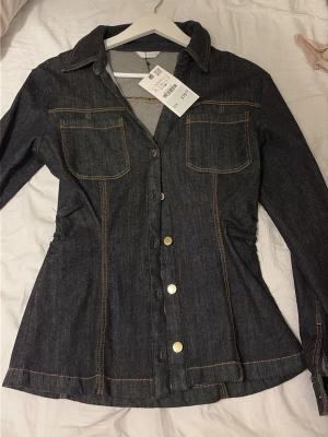 Mörk jeansjacka med guldknappar - Säljer denna super snygga jeans skjortan/tröjan, aldrig använd med prislapp. Storlek L men tycker den är liten i storleken 