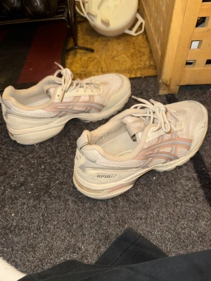 Beige ASICS 1090v2 sneakers - Säljer ett par ASICS 1090v2 sneakers i beige med ljusrosa detaljer, ny skick