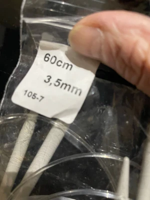 Grå rundstickor 60cm 3,5mm - Säljer ett par grå rundstickor med längd på 60 cm och tjocklek 3,5 mm. Stickorna har en slät yta och är kopplade med en transparent plastslang, perfekt för större stickprojekt som tröjor eller sjalar.