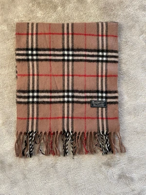 Burberry halsduk - Klassisk Burberry scarf i ikoniskt rutmönster. Mjuk och varm i 100 % kashmir med fransar nertill. Lätt att matcha och funkar till det mesta. | Mått: ca 168 × 30 cm | | Fint skick. | Hör gärna av dig vid frågor eller funderingar 😄