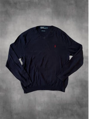 Mörkblå långärmad tröja från Polo Ralph Lauren - Tja! Säljer denna feta mörkblåa långärmade tröjan från Polo Ralph Lauren i storlek L. Tröjan är tillverkad av 100% pima bomull och har en röd broderat Ralph Lauren-logga på bröstet. Tröjan har ribbade muddar vid ärmslut och nederkant, vilket gör att tröjan hålls på plats ordentligt och inte glider runt. Perfekt för dig som gillar klassisk stil och som vill ha ett stilrent klädesplagg för en everyday-outfit. Tveka inte att höra av er vid eventuella funderingar! /Nordic Closet 