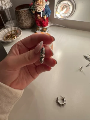 Silvrig öronring med nitar - Cool öronring i silverfärgad metall med tydliga nitar runt hela ringen. Ger en edgy vibe och passar perfekt för dig som gillar att sticka ut. Säljs styckvis.