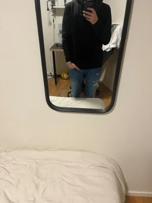 Svart hoodie med huva och snörning - Säljer en svart hoodie med huva och snörning. Tröjan har lång ärm och en klassisk loose passform som är perfekt för chill dagar. Enkel och stilren design utan mönster eller logga, passar dig som gillar basic streetwear.