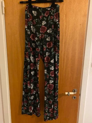 Blommiga wide pants från Hot Kiss - Säljer ett par svarta byxor med blommigt mönster från Hot Kiss. De har breda ben och hög midja. Ingen strl står men skulle säga det passar M och S. 