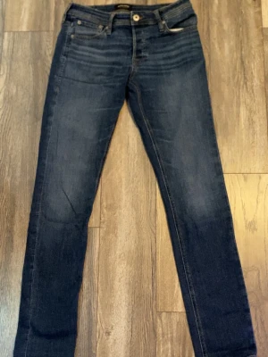 Mörkblå skinny jeans från Jack & Jones - Snygga mörkblå jeans från Jack & Jones med klassisk femficksdesign och gul kontrastsöm. Modellen är skinny fit med smal passform och tillverkad i mjukt jeansmaterial. 
