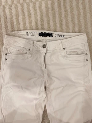 Vita jeans från Soyaconcept - Snygga vita jeans från Soyaconcept med klassisk femficksdesign och silverfärgade nitar. Byxorna har rak passform och normal midja, tillverkade i mjuk bomull med dragkedja och knapp framtill. Perfekta för dig som gillar stilrena och fräscha looks.