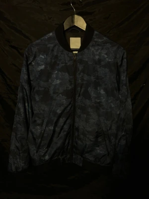 Vindjacka J.Lindeberg  - Hej, säljer nu en riktigt fet vindjacka från J.Lindeberg||storlek L (passar M)|| blått camouflage-mönster|| Jackan har två unika innerfickor som är perfekt att ha AirPods eller nycklar mm i|| Inga defekter || Färgen syns bäst på sista bilden|| Hör av dig vid frågor🙌 //StenhamCloset