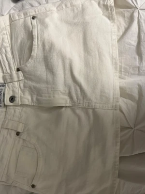 Vita jeans från Stradivarius, storlek 38 - Säljer ett par vita jeans från Stradivarius i storlek 38. Klassisk femficksmodell med raka ben och bälteshällor. Jeansen har en snygg, enkel look och är tillverkade i ett mjukt bomullstyg. Perfekta att matcha med allt i garderoben.