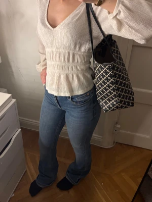 Blå bootcut jeans med normal passform - Snygga blå jeans med bootcut. De har även ett snitt på varje ben som en snygg design med det lilla extra. Använda ett fåtal gånger och köpa ifrån Veromoda. De är lite trampade på nedtill men det är inget som syns. Jag är 160cm