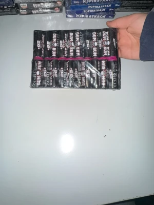 Ingen väst synlig på bilden - Bilden visar inga västar eller klädesplagg, utan föremål som ser ut att vara fyrverkerier eller smällare. Kan därför inte ge en relevant beskrivning av någon väst.