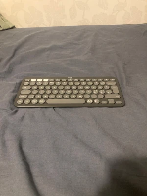 Logitech Pebble Keys 2 K380s - Snygg och kompakt trådlös tangentbord från Logitech, modell Pebble Keys 2 K380s. Perfekt för både dator och surfplatta. Rundade tangenter och smidig design. Ser ut att vara i mycket gott skick utan synligt slitage eller defekter.