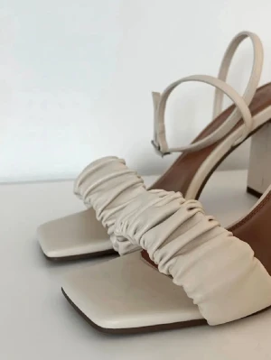 Klacksandaler med rynkning - Säljer ett par halvhöga klacksandaler med rynkning och fyrkantig tå. Justerbar ankelrem. Aldrig använda, enbart provade ett par gånger.