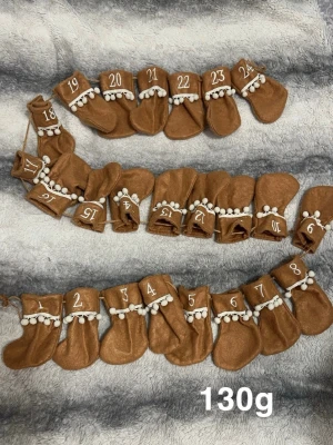 Brun julkalender med små påsar - Säljer en julkalender med 24 små bruna påsar i filtmaterial, dekorerade med vita bollar och siffror 1-24. Perfekt att fylla med små överraskningar inför december. Varje påse har en snöre för upphängning.🌸 fint använt skick 