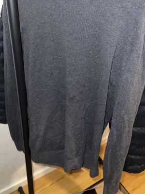 Mörkgrå stickad tröja Jack & Jones - Snygg mörkgrå stickad tröja från Jack & Jones med rund hals och lång ärm. Enkel och stilren design som passar perfekt till jeans eller chinos. Mjuk och skön kvalitet, perfekt för kyliga dagar. Storlek S men passar M också 