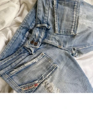 Ljusblå slitna Diesel bootcut jeans - Säljer ett par ljusblå slitna Diesel jeans med låg midja och bootcut passform. ❌Står storlek w27 med sitter som w25!!!❌ alla hålen är lappade och lagade men det ger en riktigt snygg detalj till jeansen så de sticker ut lite, vilket jag verkligen gillar!🤩