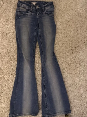 Blå bootcut kvarg jeans  - Snygga blå jeans med bootcut-snitt och coola slitningar på framsidan. Använda endast få antal gånger och har inte något tecken på användning! Finns inte kvar i butik.
