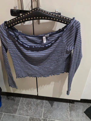 Randig långärmad topp från H&M - Säljer en långärmad topp från H&M Basic i storlek XL. Toppen är randig i mörkblått, vitt och ljusblått med volangkant vid halsringning och nederkant. Materialet är mjuk bomull med stretch för skön passform. Perfekt att styla med jeans eller kjol.