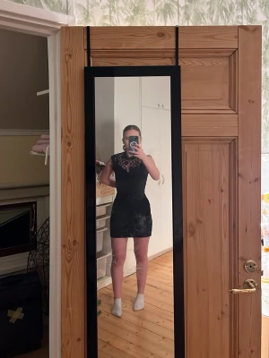 Svart spetsklänning med öppen rygg - Säljer en svart kort klänning med spetsdetaljer upptill och snygg öppen rygg. Klänningen är tight och har ärmlös design med rund halsringning. Perfekt för dig som vill ha en stilren och elegant look med lite edge. Fråga mig om ni undrar något 😊