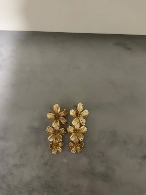 Guldiga blomm-örhängen - Säljer dessa jättefina blomörhäbgen ifrån glitter som endast användes 1 gång, under min bal🥰 Får ingen användning för dem längre så kände att de va värt att försöka sälja dem vidare❤️❤️inga defekter alls! 