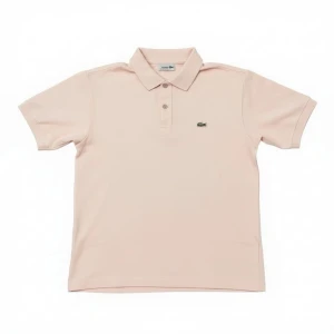 Ljusrosa piké från Lacoste - Säljer en ljusrosa pikétröja från Lacoste med klassisk krage och två knappar framtill. Tröjan har korta ärmar och den ikoniska krokodilloggan broderad på bröstet. Perfekt för en chill och stilren look.