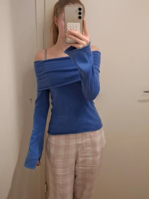 off shoulder tröja - Säljer en blå off shoulder topp från ONLY i storlek XS. Tröjan har lång ärm och en snygg omlott-effekt över axlarna. Perfekt för dig som gillar en stilren och trendig look. Materialet känns mjukt och stretchigt.