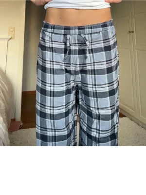 Rutiga pyjamasbyxor - Säljer ett par blårutiga mjukisbyxor med snörning i midjan.🥹 Byxorna har en loose passform och är tillverkade i mjukt bomullsmaterial. 🥰Perfekta för chill dagar hemma. Mönstret är klassiskt rutig i olika blå och grå toner. Är öppen för lägre priser, kolla gärna in mina andra annonser så kan du få rabatt💘