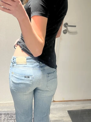 Ljusblå bootcut jeans från Lee - Säljer ett par ljusblå jeans från Lee med klassisk bootcut passform. Jeansen har låg midja, raka ben och snygga bakfickor med Lee-logga. Storlek W26 L31. 37cm midjemått och 77cm innerbenslängd 