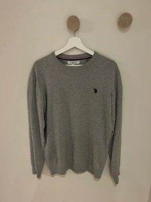Grå tröja från U.S Polo ASSN. - Snygg grå tröja från U.S. Polo Assn i storlek M. Sitter riktigt fint och en riktigt schysst tröja för vintern!