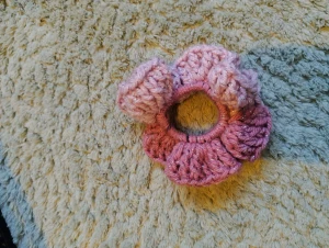 Rosa virkad scrunchie med glitter - Superfin handvirkad scrunchie i olika rosa nyanser med glittriga inslag. Den har en blomformad design som ger en söt och unik look till din frisyr. Perfekt för att piffa upp håret med lite extra färg och glans. Virkad av mig!