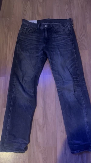 Levi's mörkgrå jeans straight fit - Säljer ett par Levi's jeans i mörkgrå tvätt med klassisk femficksdesign och raka ben. Jeansen har normal passform och är tillverkade i robust denim. Perfekta för dig som gillar en tidlös och avslappnad stil.