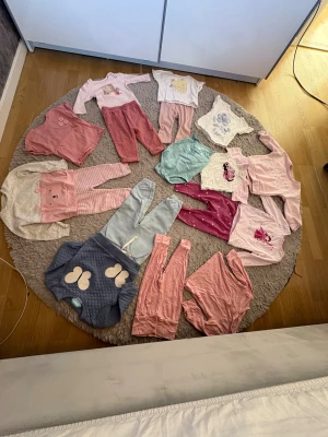 Söta barnleggings i rosa och pastell - Flera par barnleggings i olika nyanser av rosa och pastell, vissa med prickigt eller ribbat mönster. Byxorna är mjuka och bekväma, perfekta för lek och vardag. Materialet är bomull och syntet, och färgerna går i rosa, ljusblått och beige.