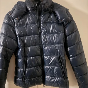 Mörkblå pufferjacka från 157 - Snygg mörkblå pufferjacka från 157 med glansig yta och quiltad design. Knappt använd!