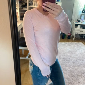 Ljusrosa stickad tröja med rund hals - Säljer en ljusrosa stickad tröja med rund halsringning och långa ärmar. Tröjan har en enkel och clean design, perfekt att matcha med jeans eller kjol. Mjuk och skön känsla, passar dig som gillar en basic men söt stil.