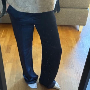 Satin/sidenbyxor - Säljer ett par mörkblå siden/satinbyxor från NAKD med raka, lite vidare ben och klassisk passform. Byxorna har diskreta fickor bak och är perfekta för en clean och stilren look. Materialet känns mjukt och följsamt, och midjan är normalhög. Stl 32 men är stretchiga och passar större storlekar också!