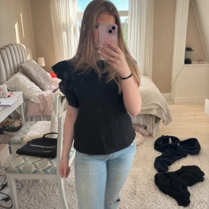 Svart blus med volangärm från Zara - Supersnygg svart blus från Zara med breda volangärmar i broderad spets. Toppen har rund halsringning och är tillverkad i mjuk bomull. Inte använd alls mycket 