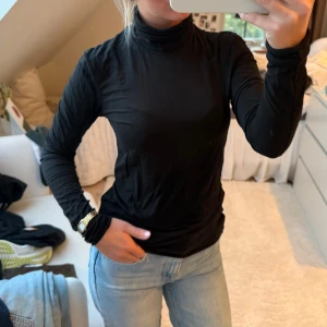 Svart polotröja i bomull, stl S - Svart polotröja i mjuk bomull med lång ärm och klassisk hög krage. Sitter snyggt och är enkel att matcha till jeans eller kjol. 