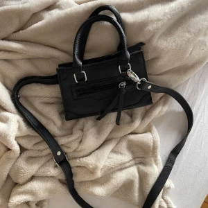Väska  - Snygg svart minihandväska i skinnimitation med både handtag och justerbar axelrem. 