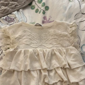 Beige spetsblus med volanger från Zara - Supersöt beige blus från Zara med spetsdetaljer och volanger. Blusen har korta ärmar med spets och ett vackert blommönster upptill. från Zara slut såld och varit svårt att få tag på❣️