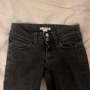 Svarta bootcut jeans med broderad ficka - Snygga svarta jeans från Gina Tricot med bootcut-ben och cool tvättad look. Byxorna har dubbla knappar i midjan och en broderad bakficka som extra detalj. Perfekta för dig som gillar en trendig och avslappnad stil.